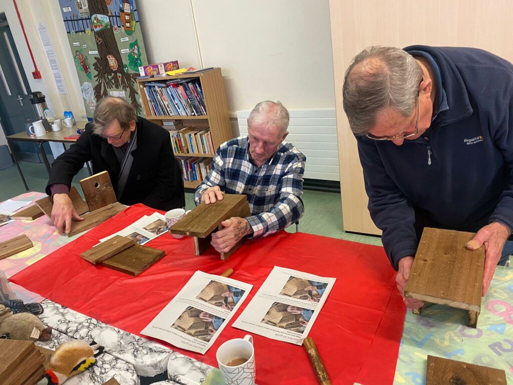 Photo of Men constructing wooden bird house.
