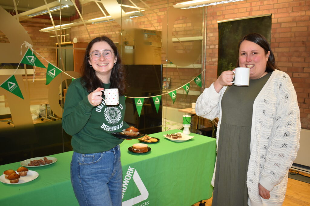 Two people holding a cup of tea and eating cake