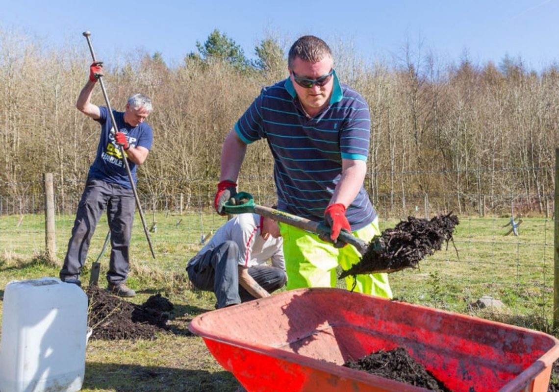 Volunteer shoveling soil into wheelbarrow.