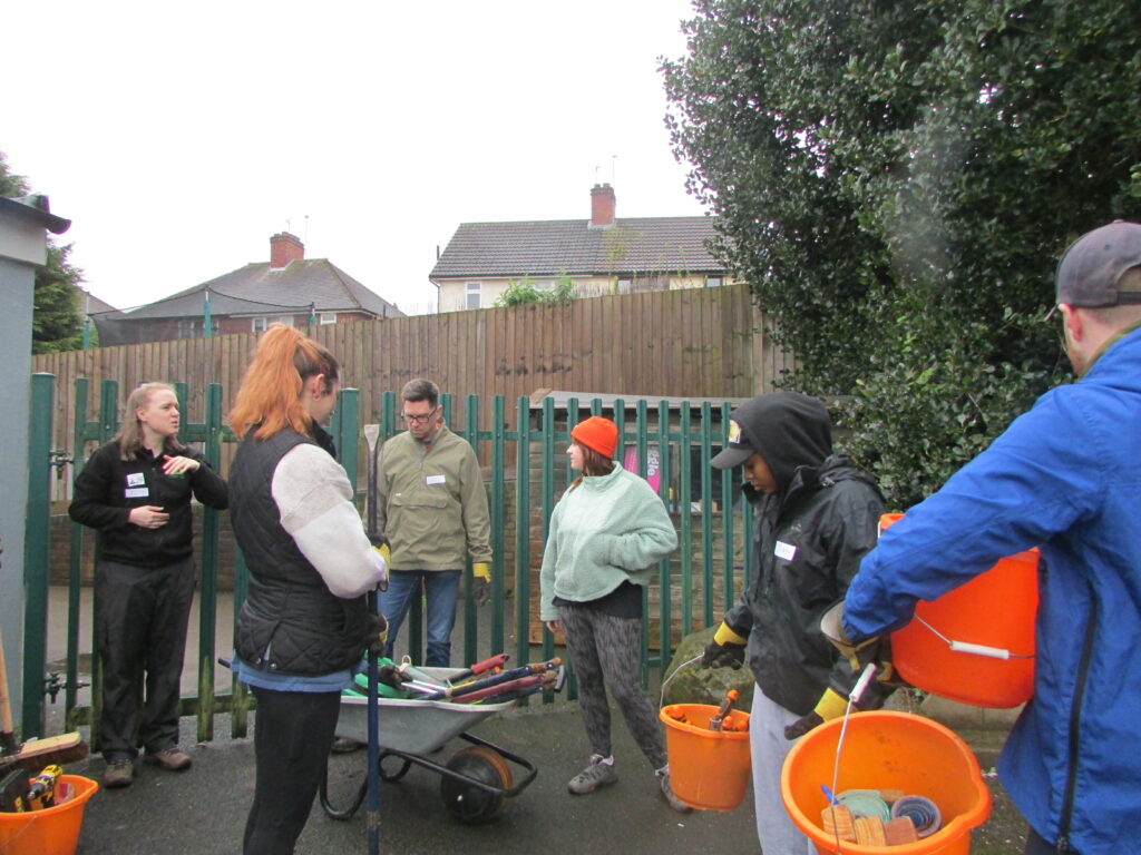 Photo of volunteer workers at the Annie Lennard Primary School, holding buckets of gardening equipment.