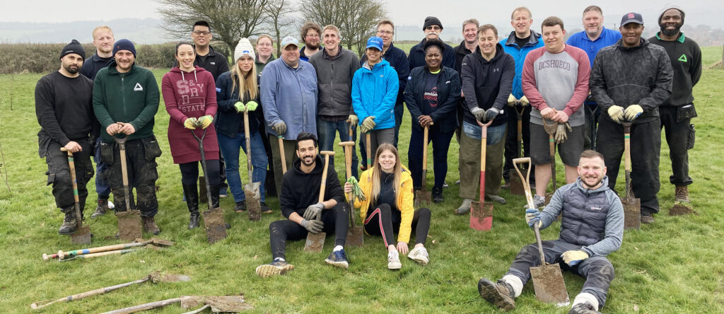 Group of people holding shovels in outdoor setting.