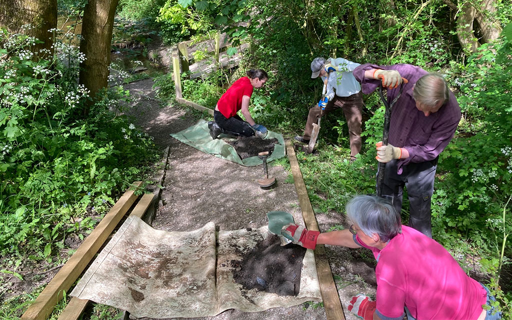 Group of people working on laying a path in outdoor setting.