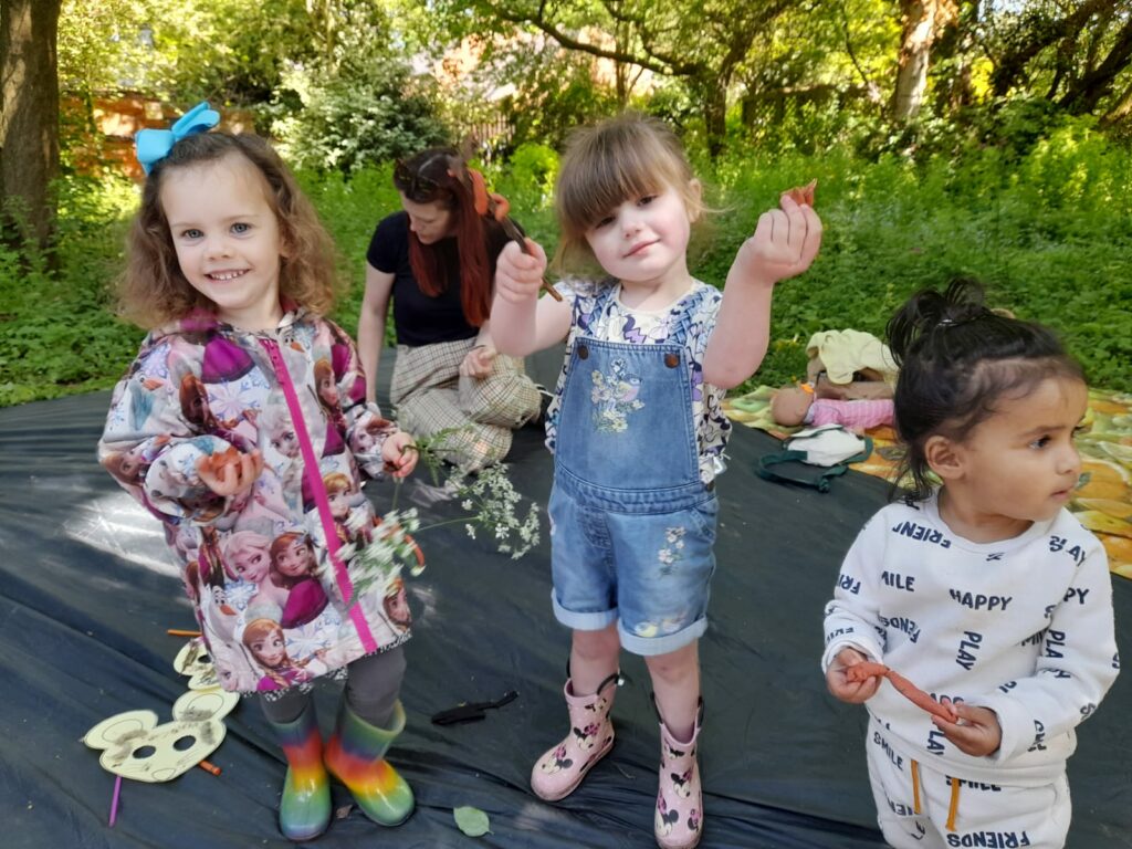 Three children holding clay animals in outdoors setting.