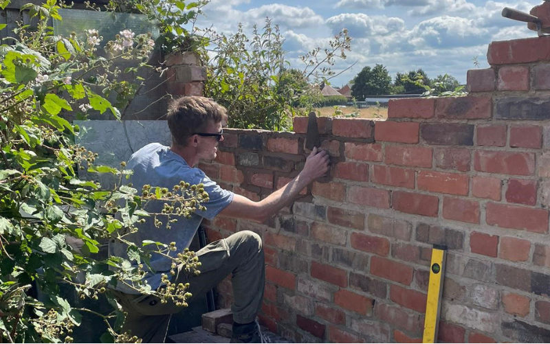 Young man laying bricks in outdoor space